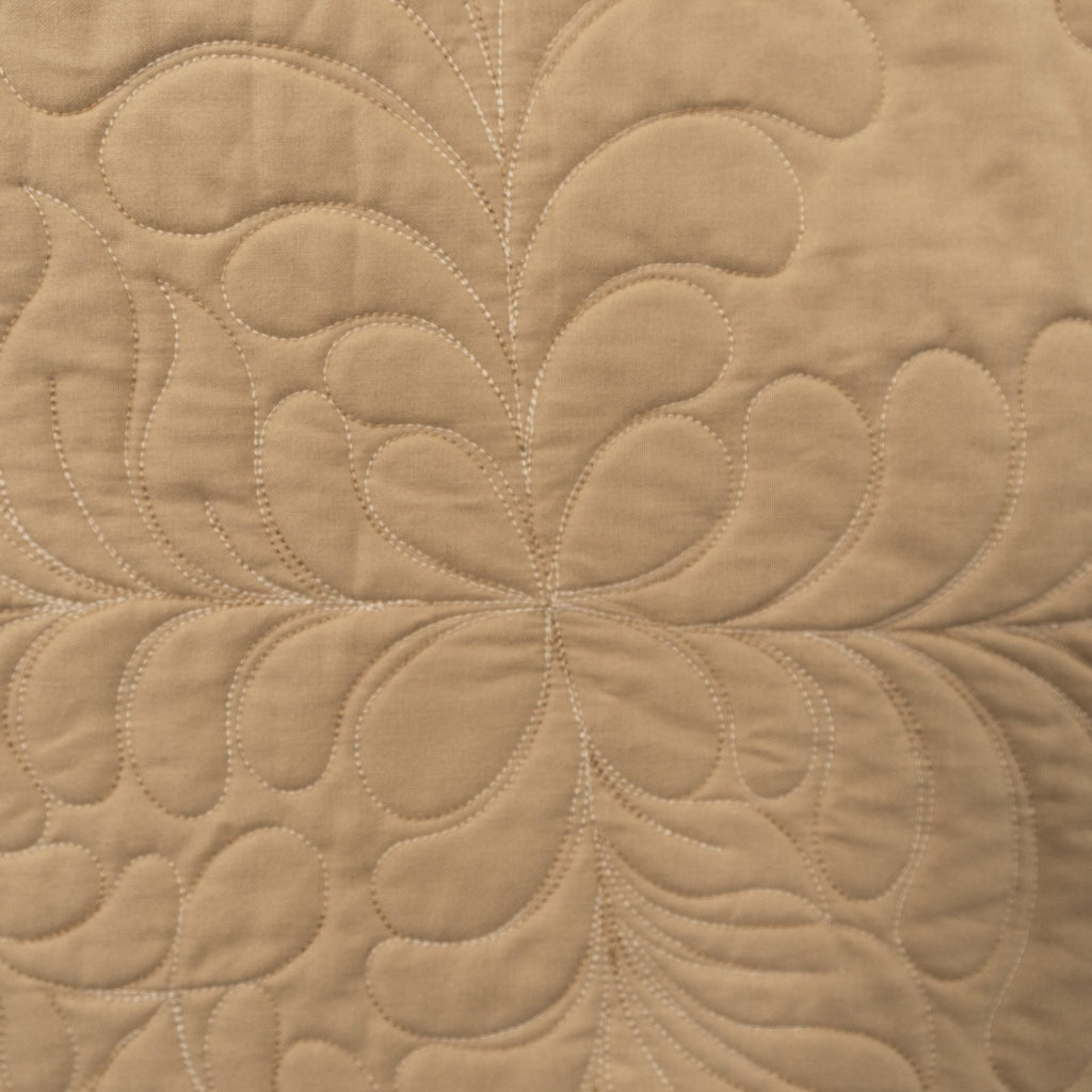 Close-up of beige quilted fabric with a floral pattern