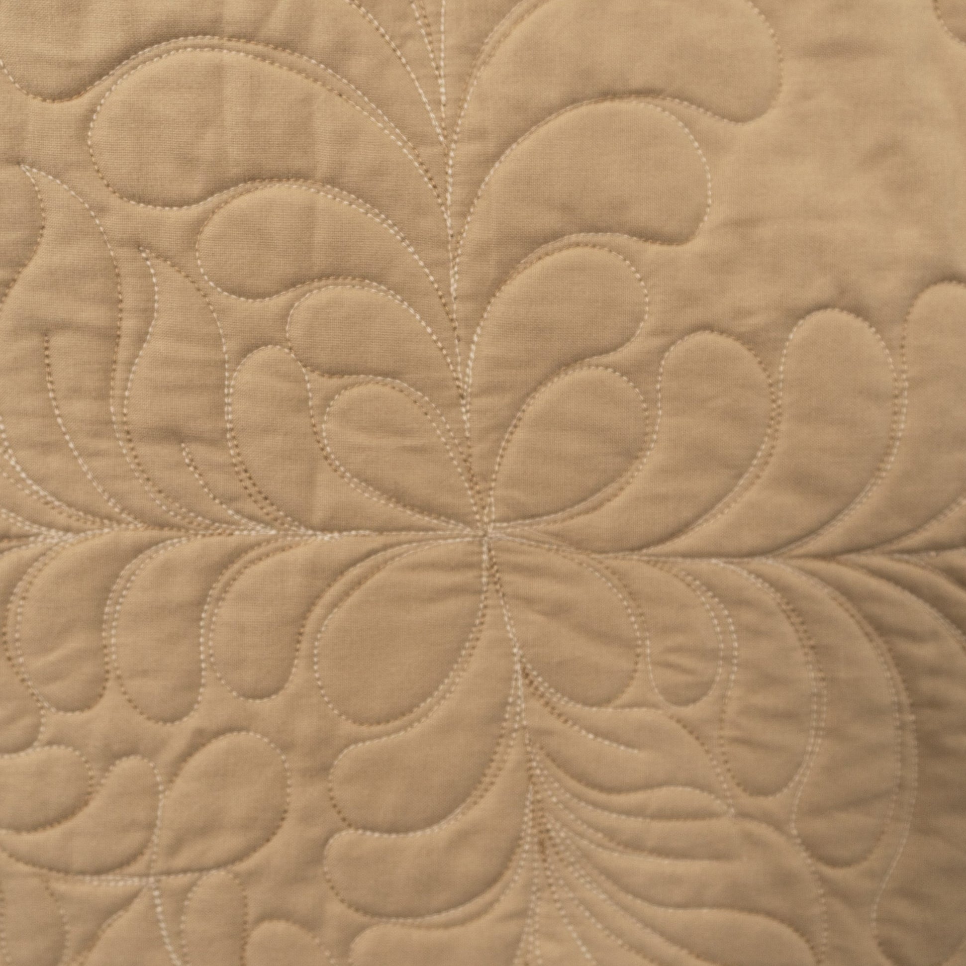 Close-up of beige quilted fabric with a floral pattern