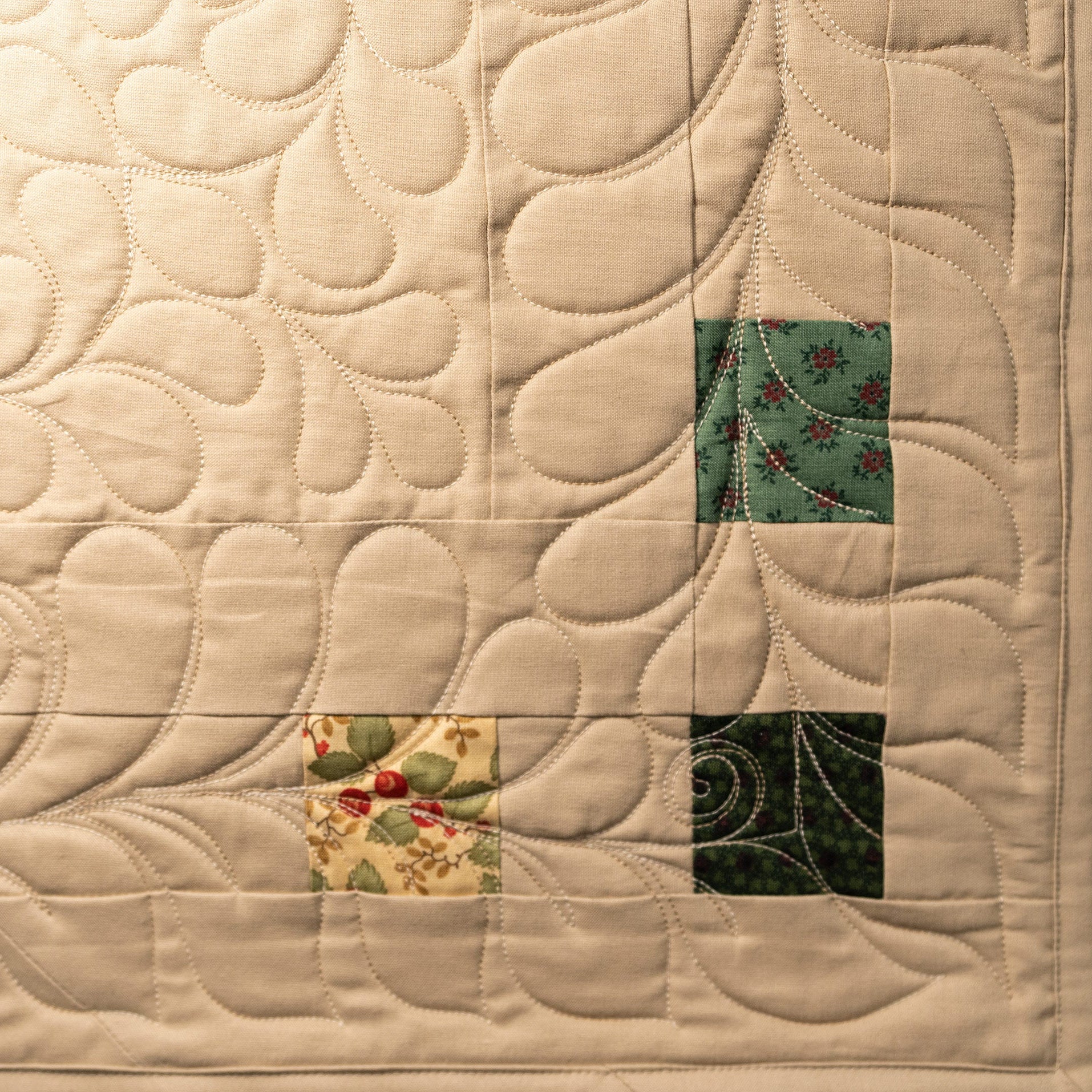 Quilt with intricate stitching and colorful square patterns on a beige background