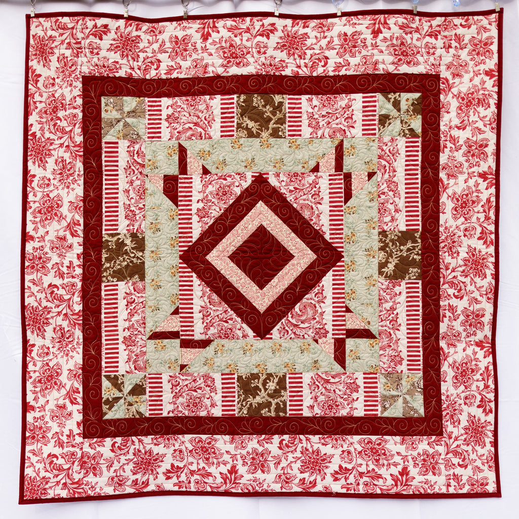 Quilt with geometric pattern and floral border on a white background