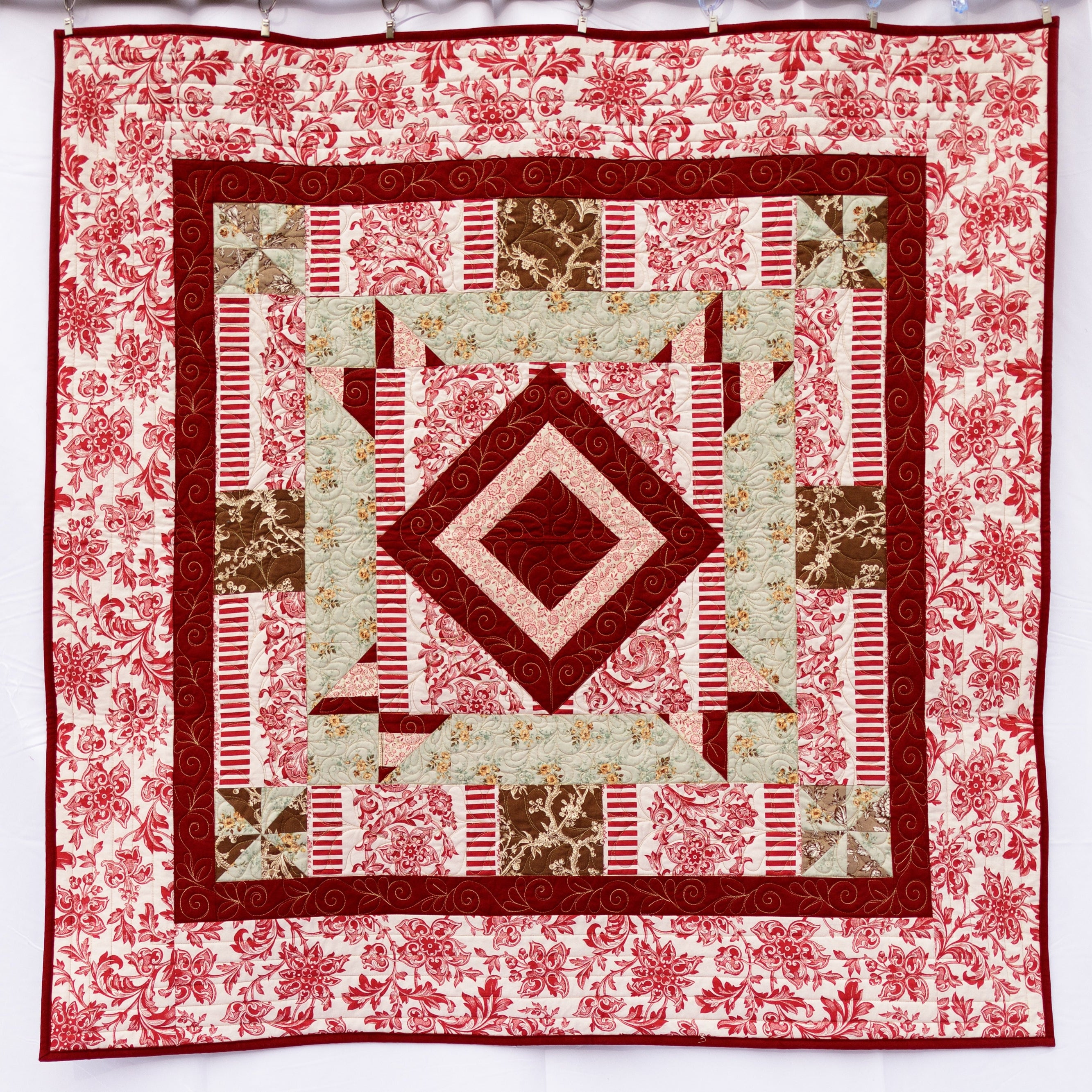 Quilt with geometric pattern and floral border on a white background