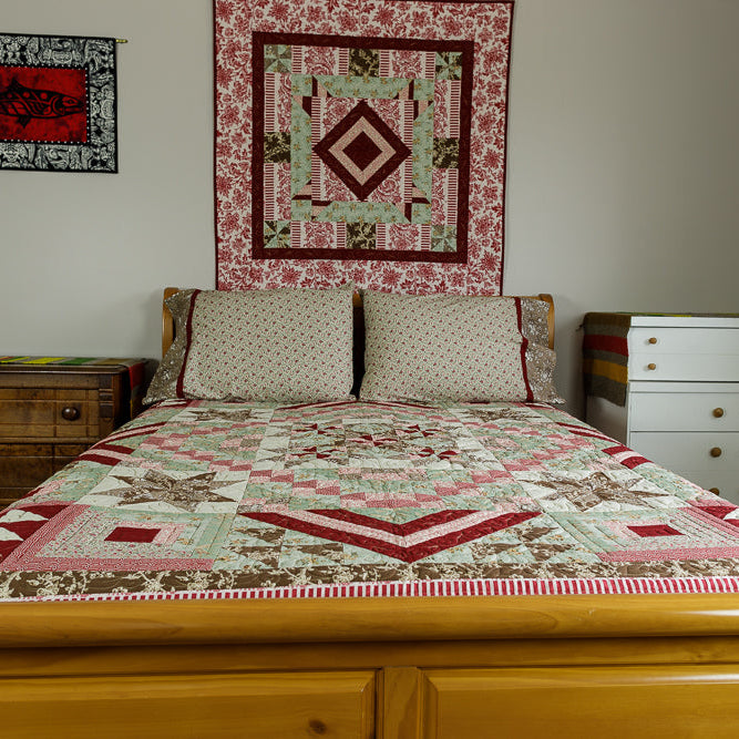 Bedroom with wooden bed, quilted bedding, and wall hangings.