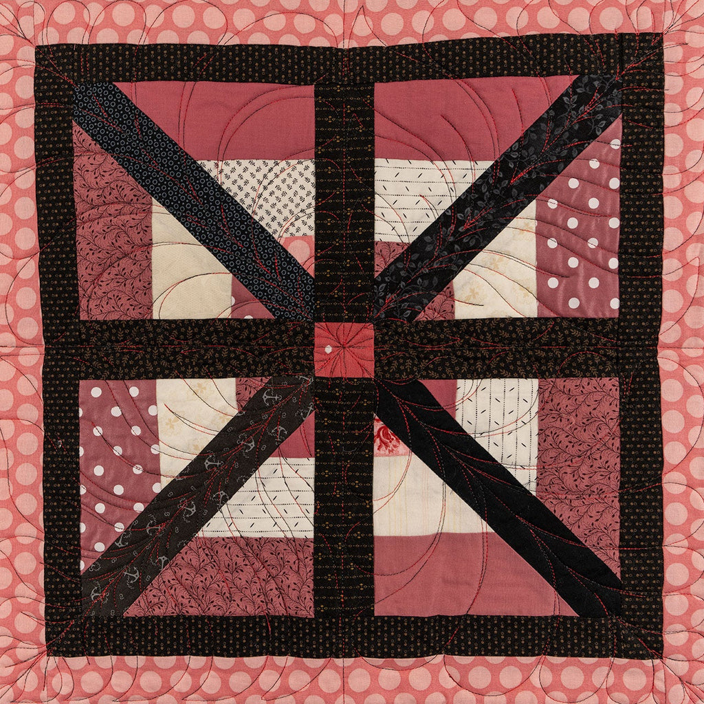A close up of a quilt block showing a square floral print with a pink polkadot border.