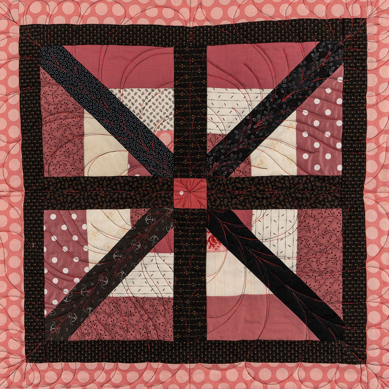 A close up of a quilt block showing a square floral print with a pink polkadot border.