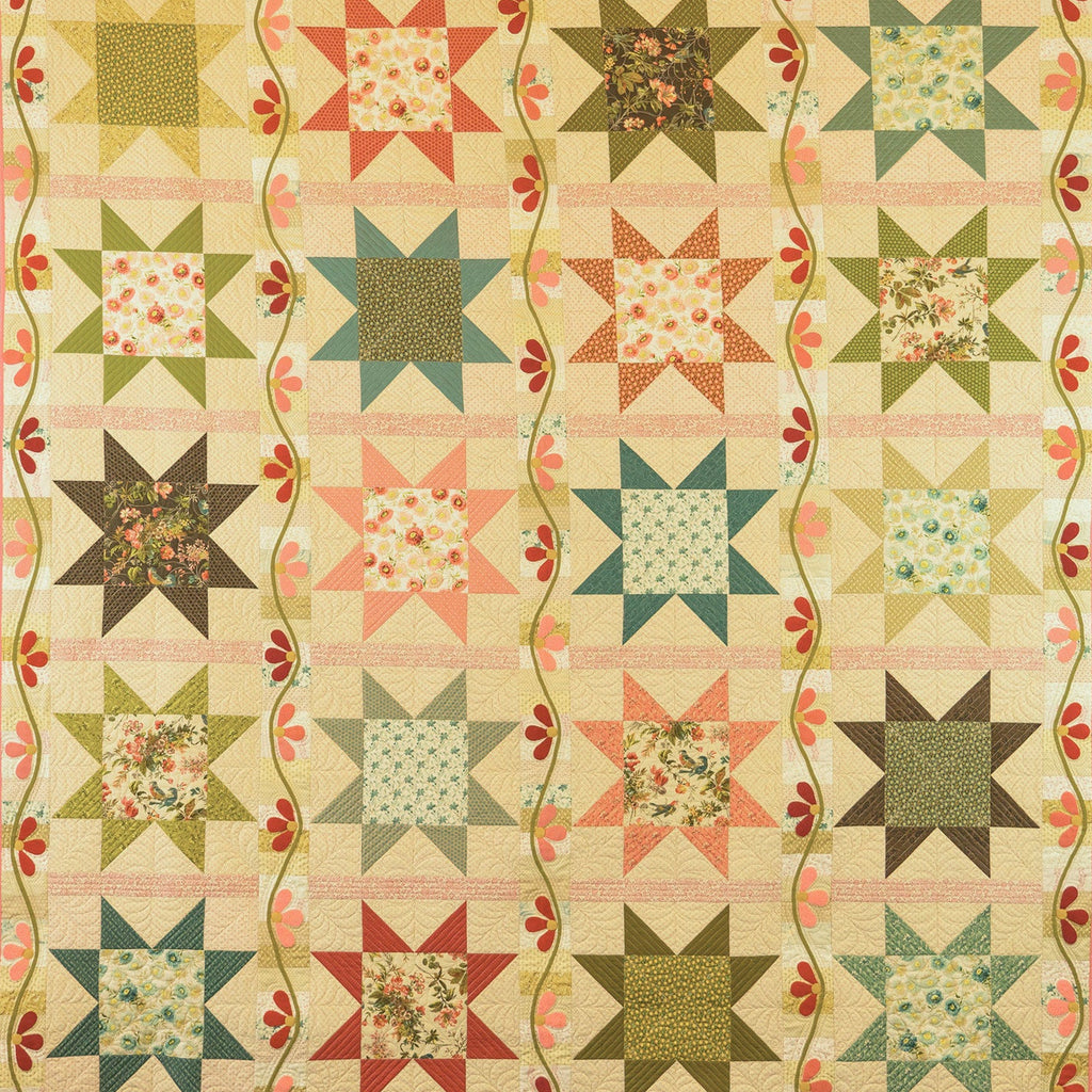 A vintage quilt with a repeating star and floral block pattern, featuring a cream background with green, red, and blue star motifs and wavy floral borders.