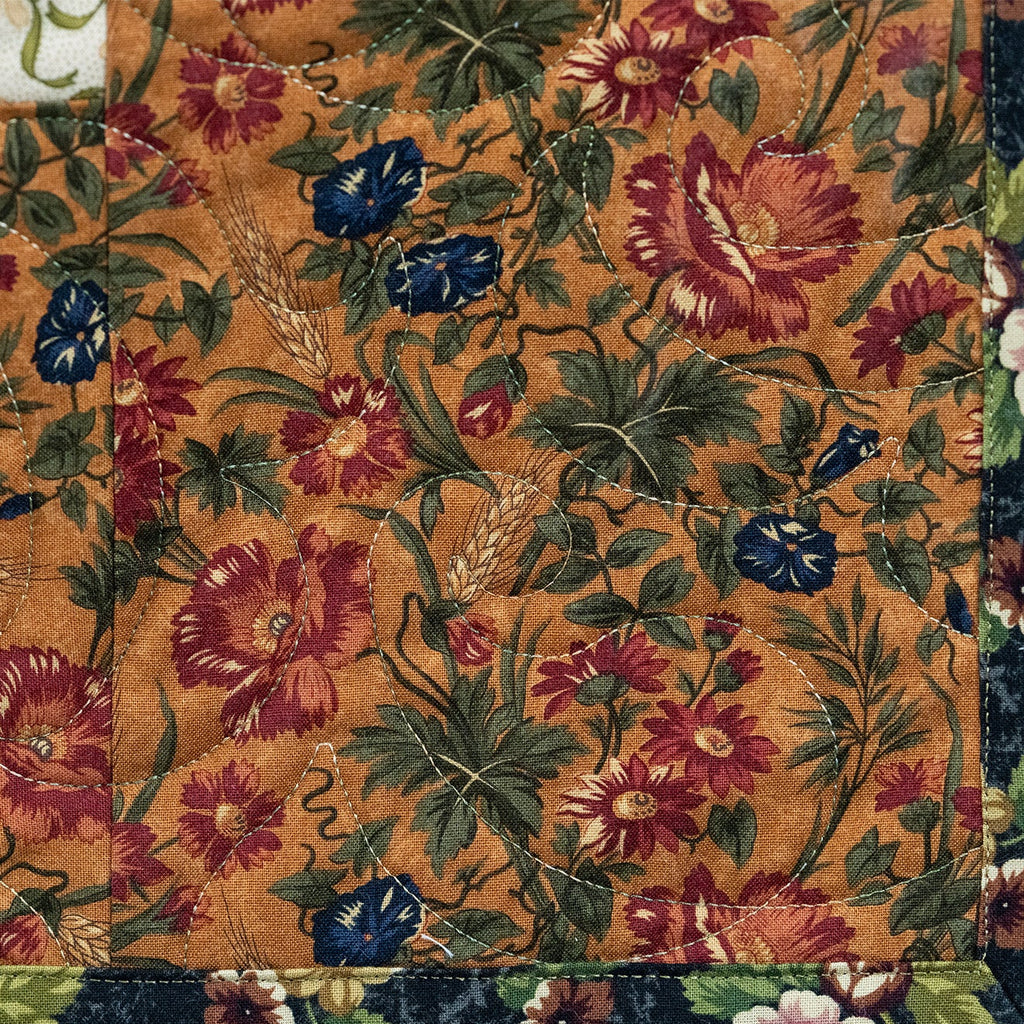 Floral patterned fabric with red, blue, and green flowers on a brown background