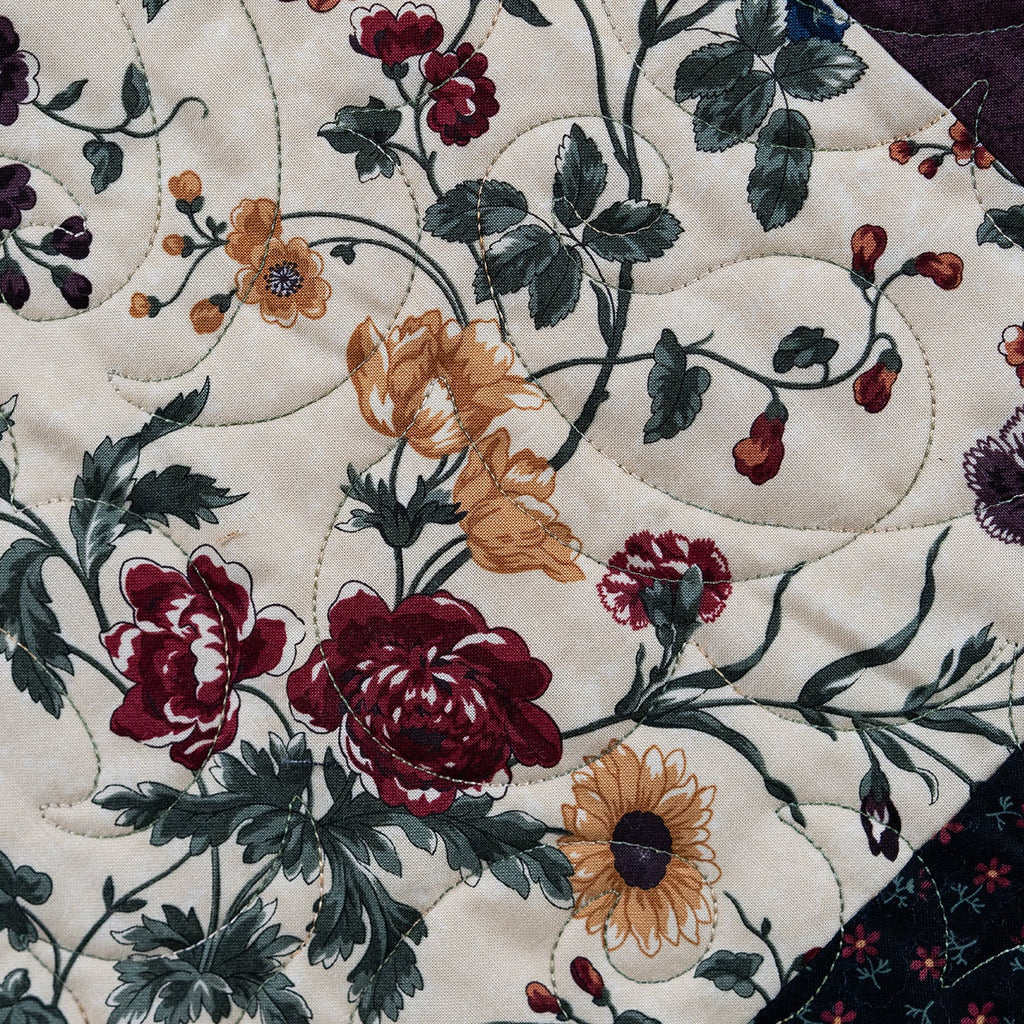 Close-up of a floral quilt with sunflowers and other flowers on a white background