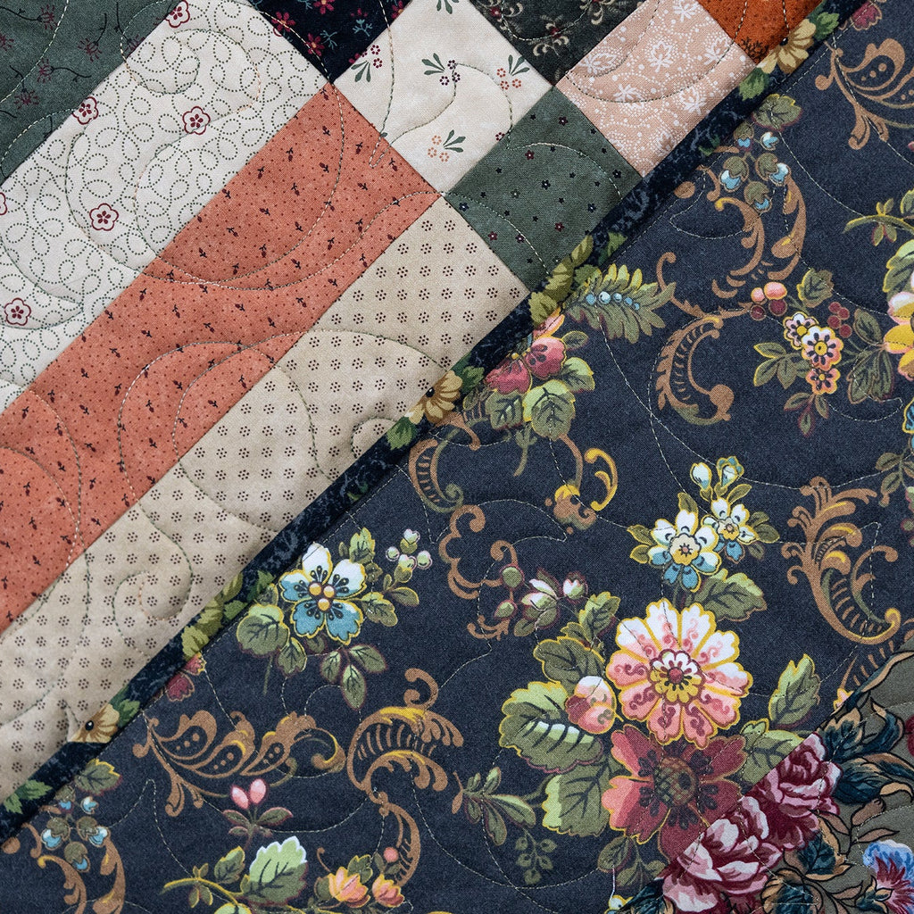 Close-up of a patchwork quilt with floral and geometric patterns.