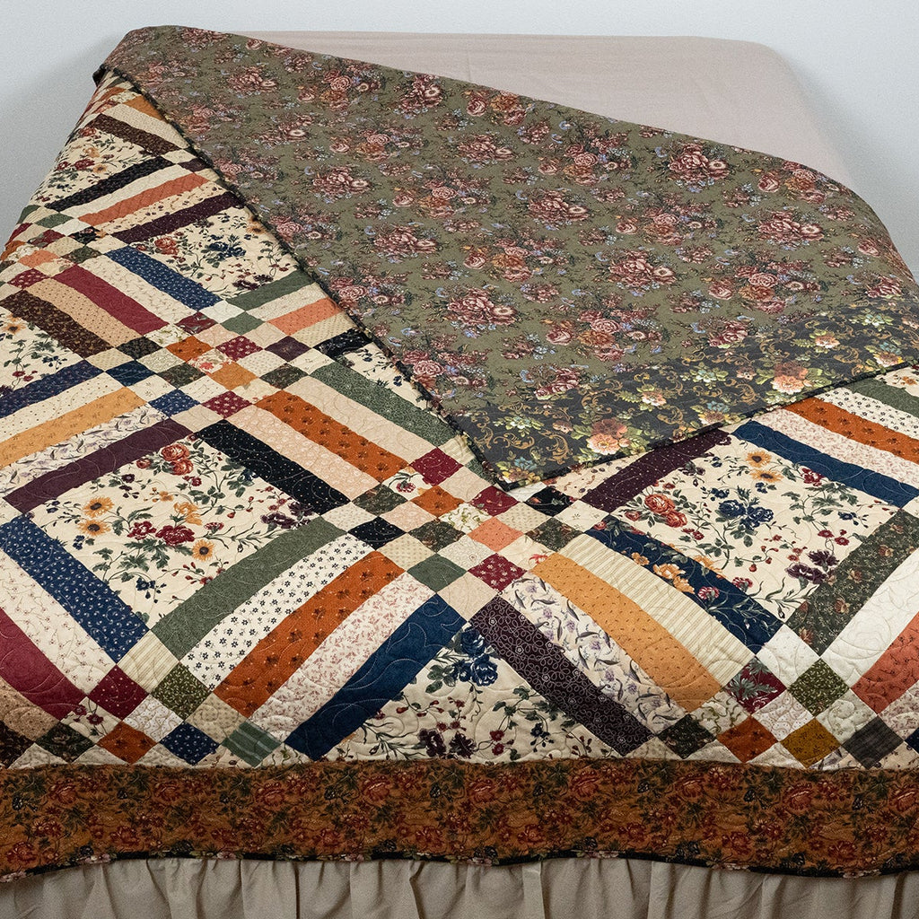 Quilt with geometric pattern on a bed against a white wall