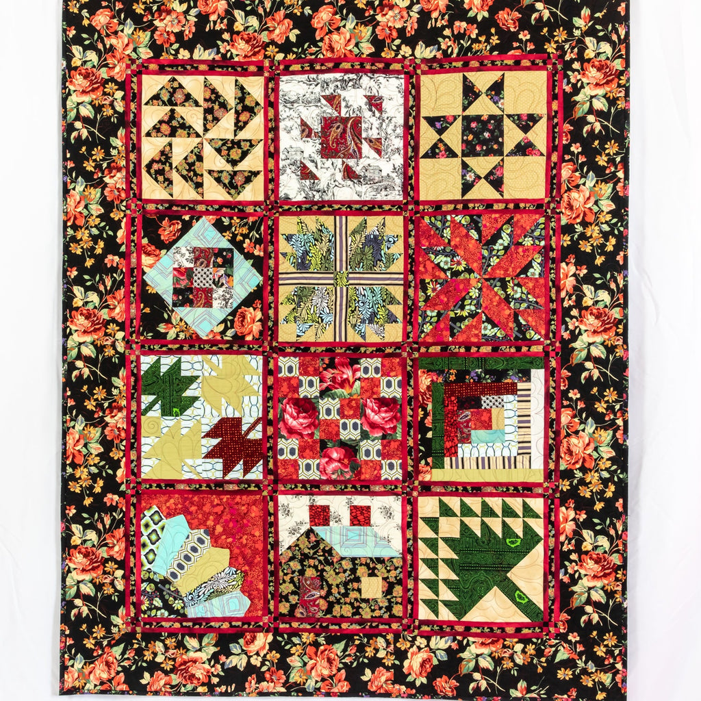 A square quilt featuring a 4x3 grid of colorful patchwork blocks surrounded by a black floral border. The patchwork includes red, yellow, green, blue, and brown patterns, with red borders between each section.