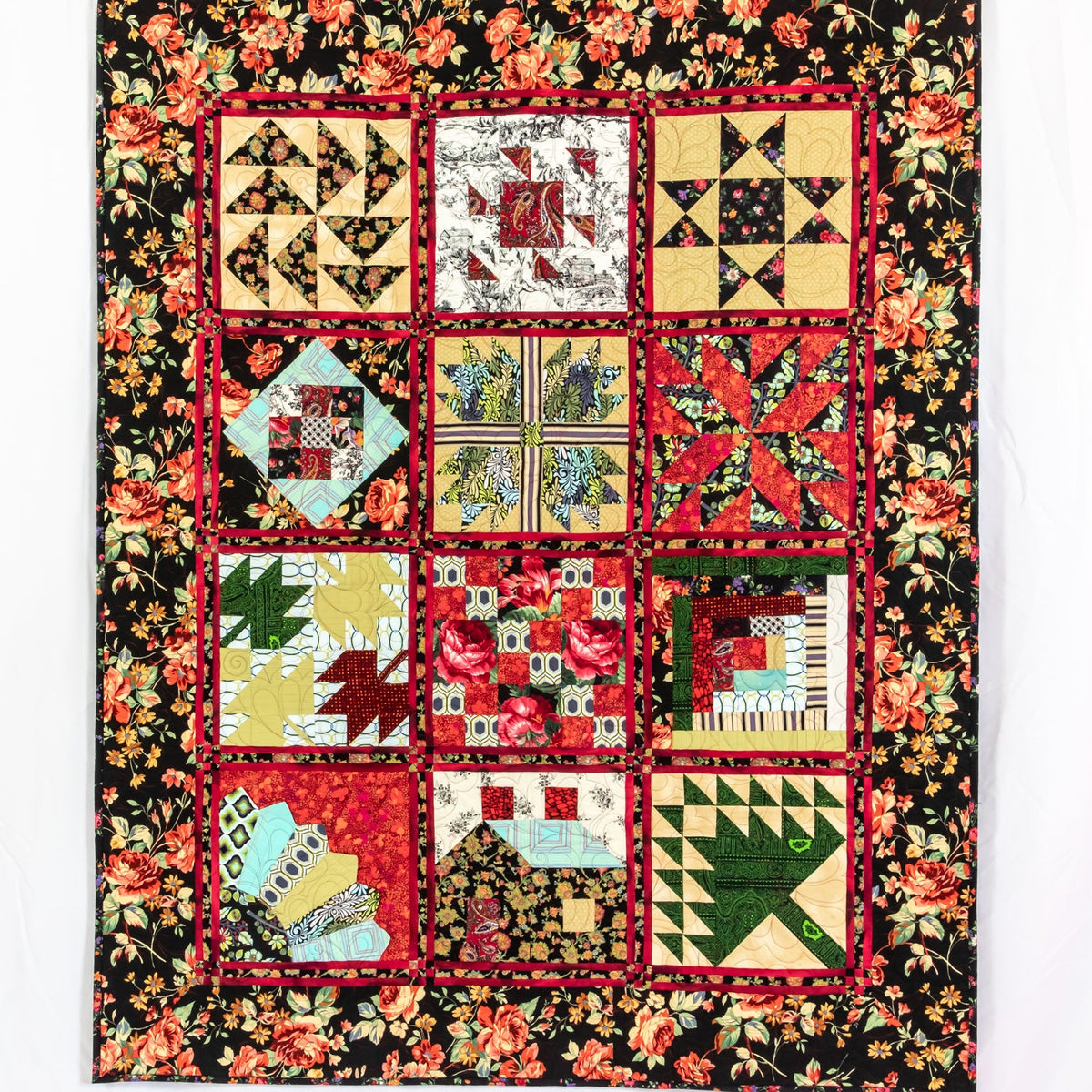 A square quilt featuring a 4x3 grid of colorful patchwork blocks surrounded by a black floral border. The patchwork includes red, yellow, green, blue, and brown patterns, with red borders between each section.