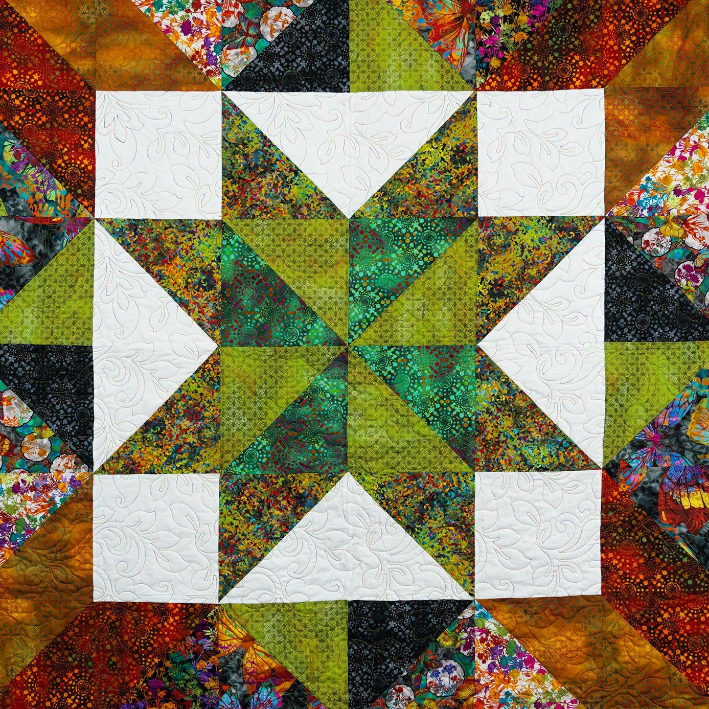 Colorful quilt with geometric pattern featuring triangles and squares.