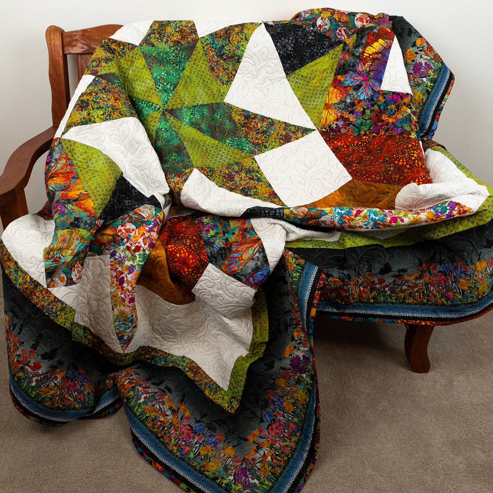 Colorful quilt draped over a wooden chair on a plain background