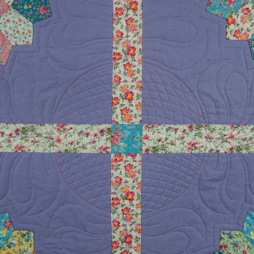 Quilt with floral border and corner pieces on a purple background