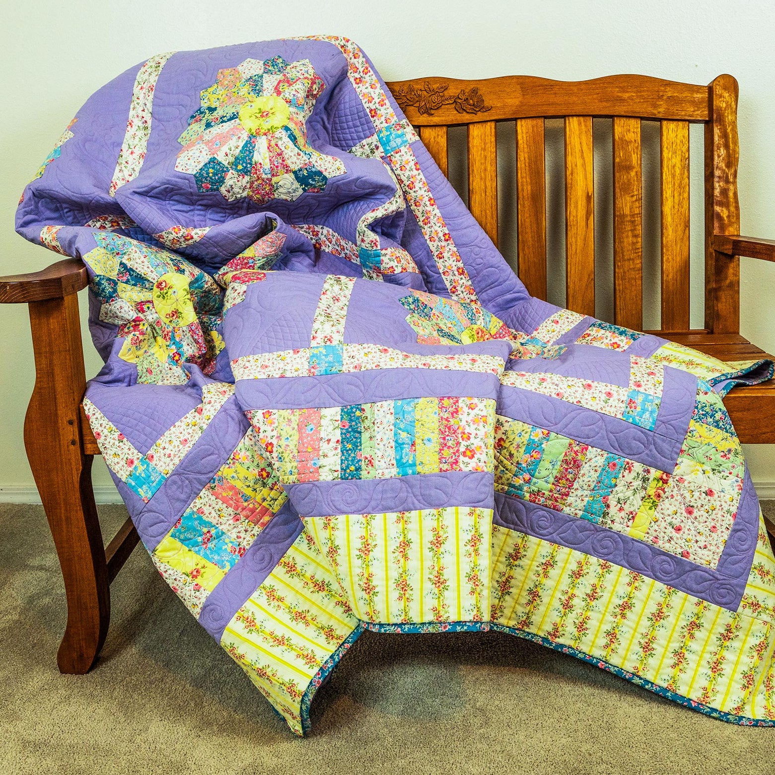 Colorful patchwork quilt draped over a wooden chair against a plain wall.
