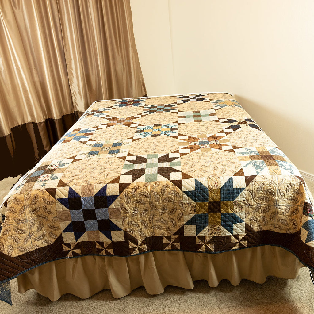 Quilted bedspread with geometric pattern on a bed in a room with curtains.