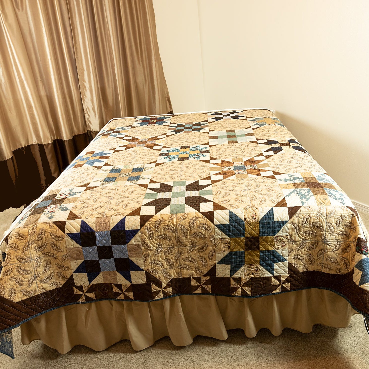 Quilted bedspread with geometric pattern on a bed in a room with curtains.