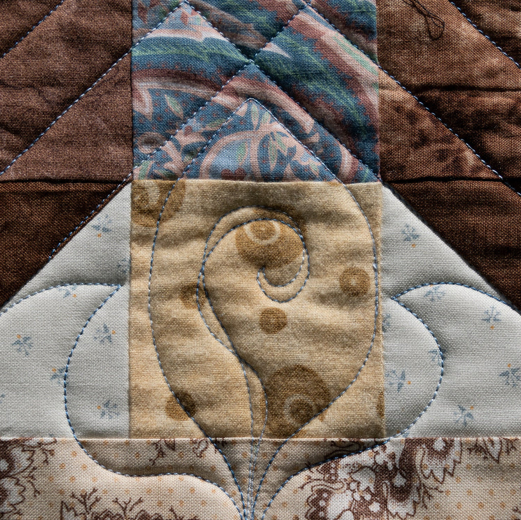 Close-up of a quilted fabric block with a floral design.