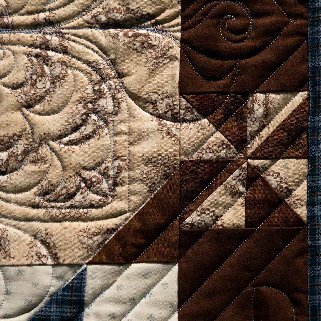 Close-up of a patchwork quilt with brown and beige patterns