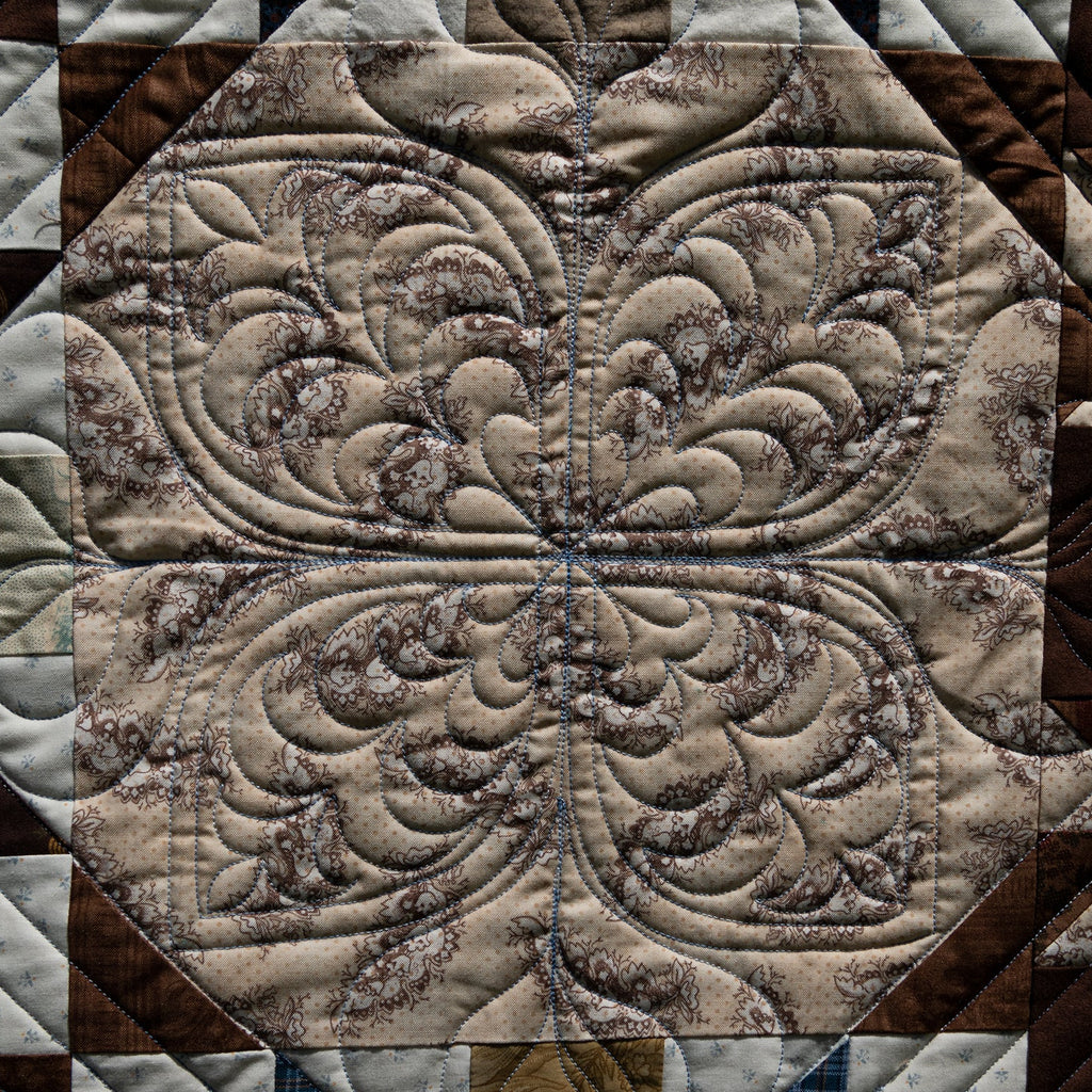 Close-up of a quilt with intricate pattern in brown and beige tones