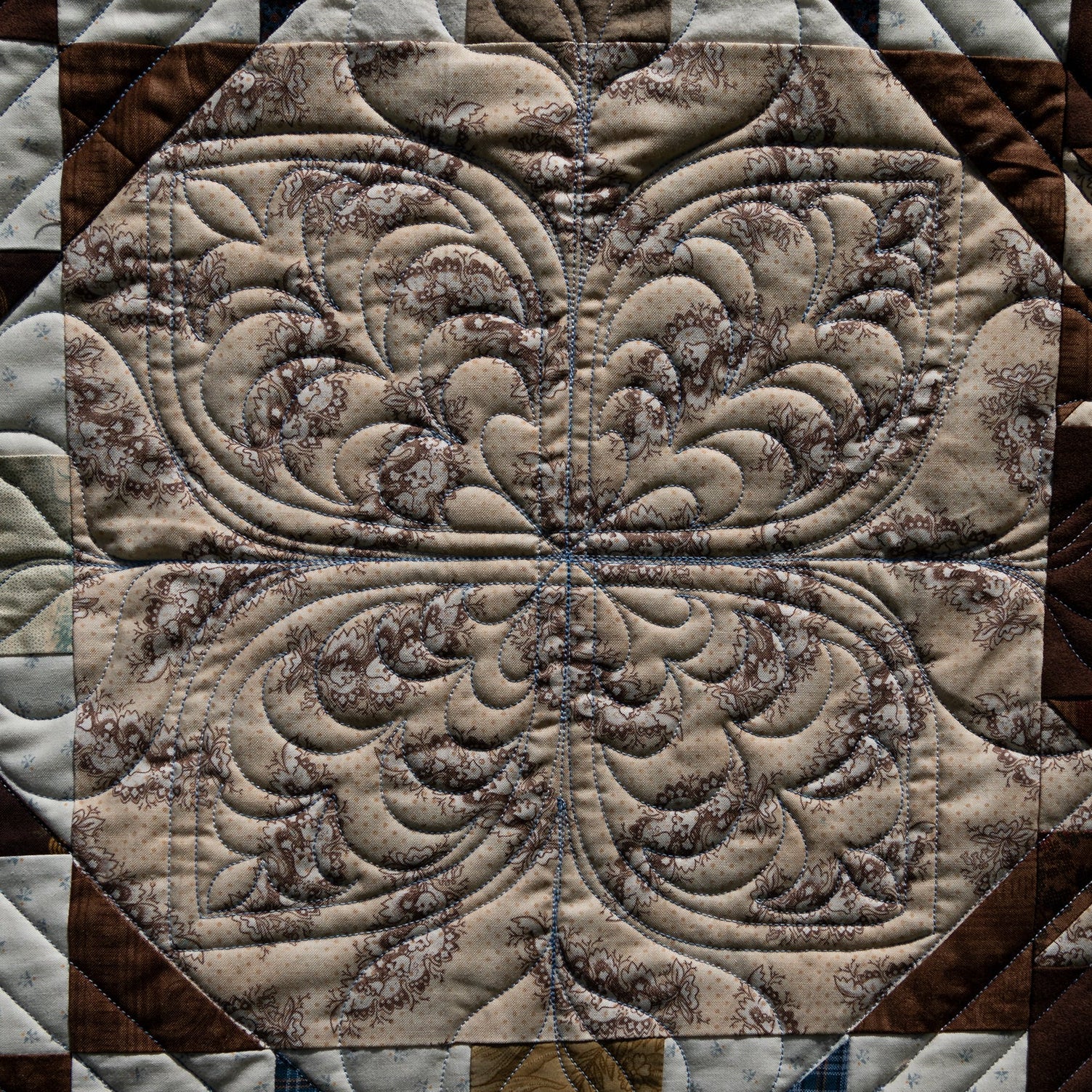 Close-up of a quilt with intricate pattern in brown and beige tones