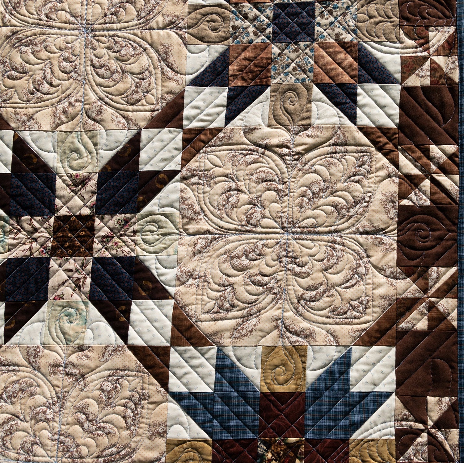 Close-up of a quilt with intricate patterns in brown, beige, and blue.