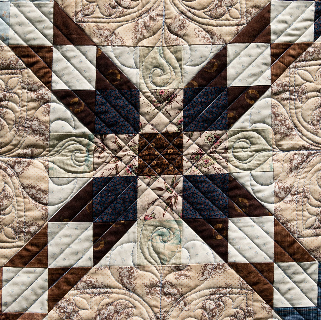 Quilt with intricate patterns in brown, beige, and blue tones.