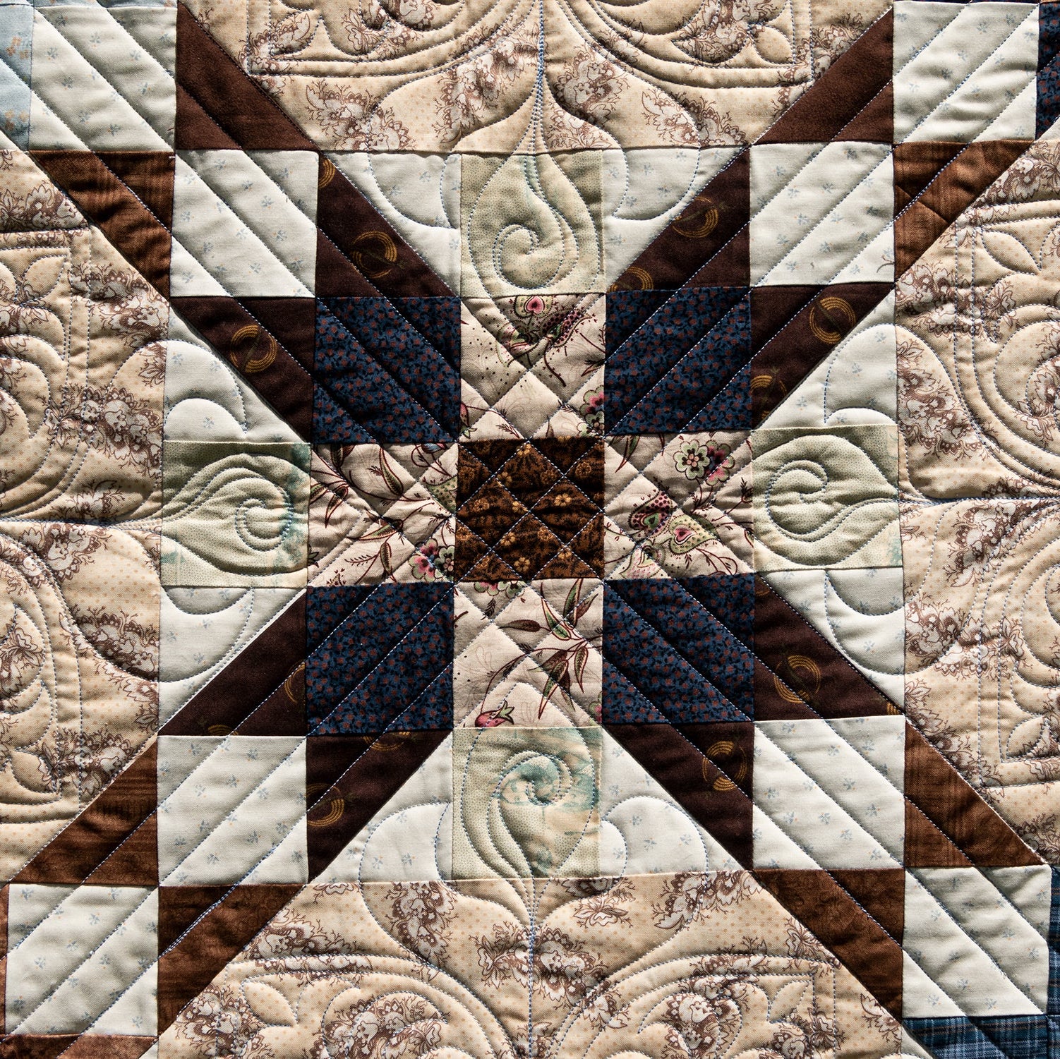 Quilt with intricate patterns in brown, beige, and blue tones.