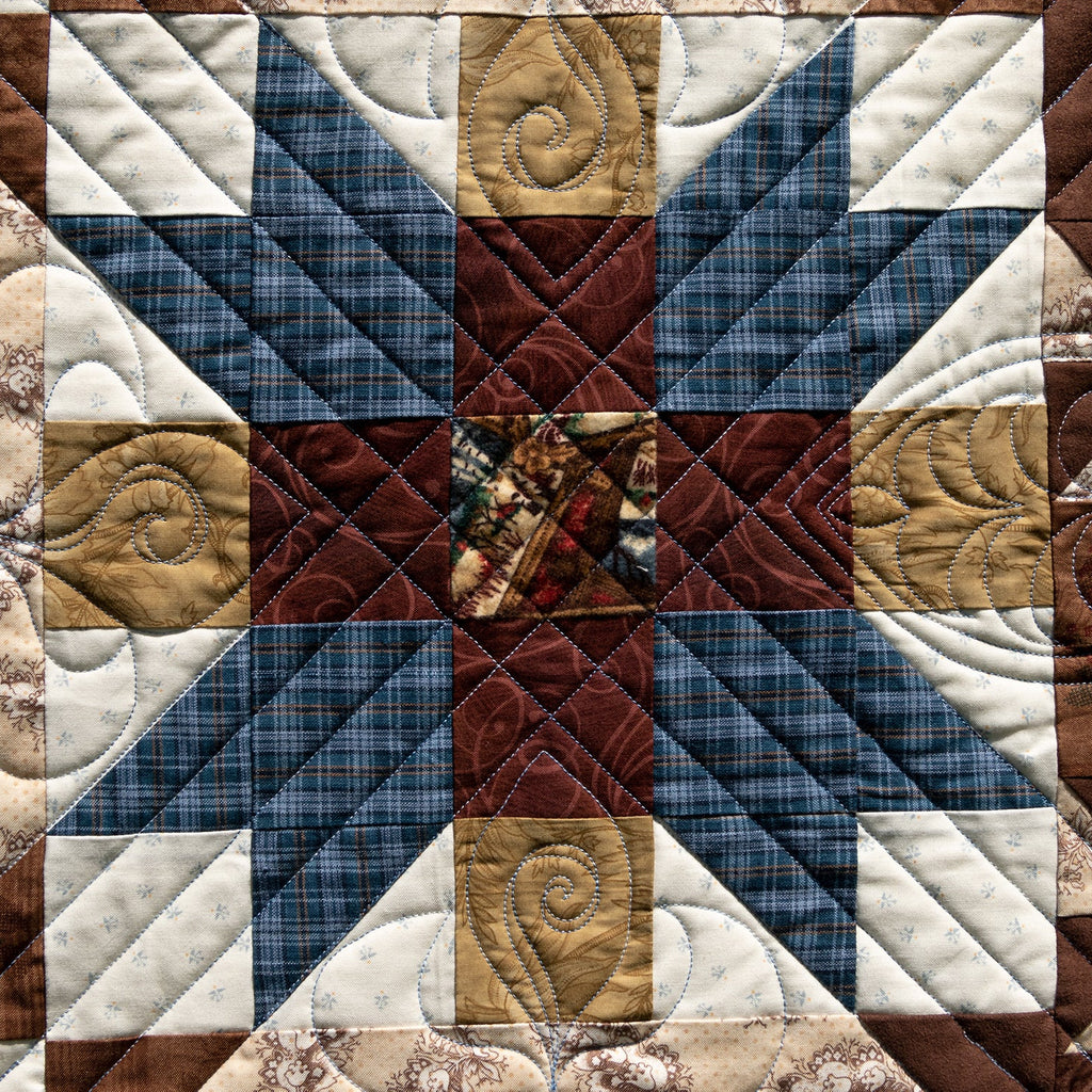 Quilt with patchwork pattern featuring blue, brown, and beige colors.