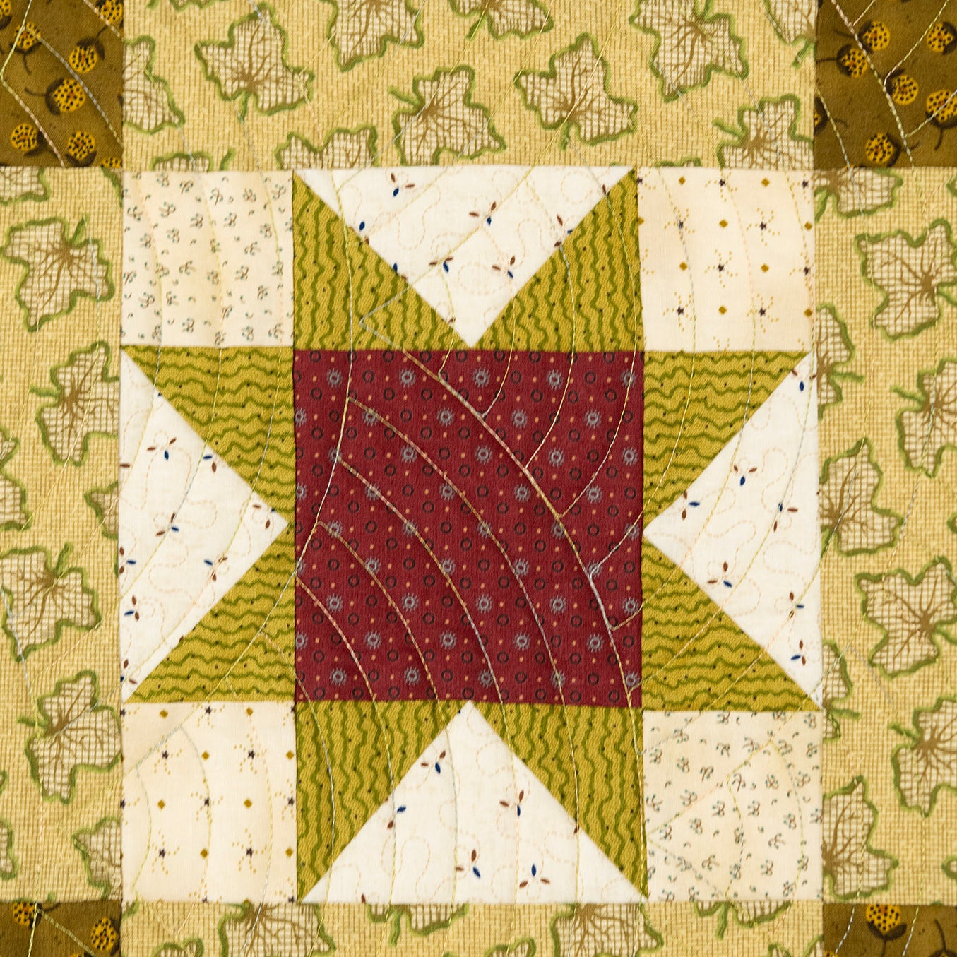 Quilt block in a star pattern in red and green with a leaf print border