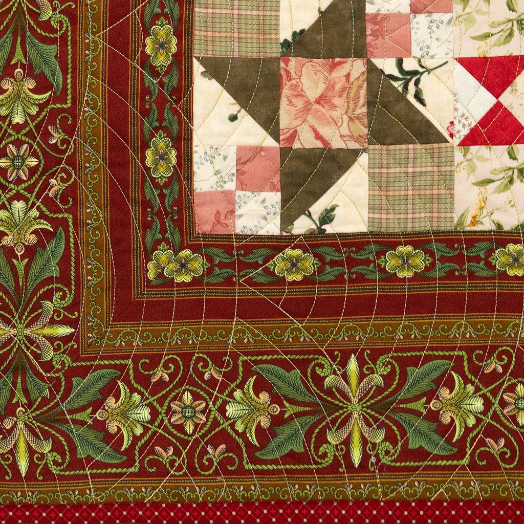 Quilt block with an intricate floral print in dark red and green