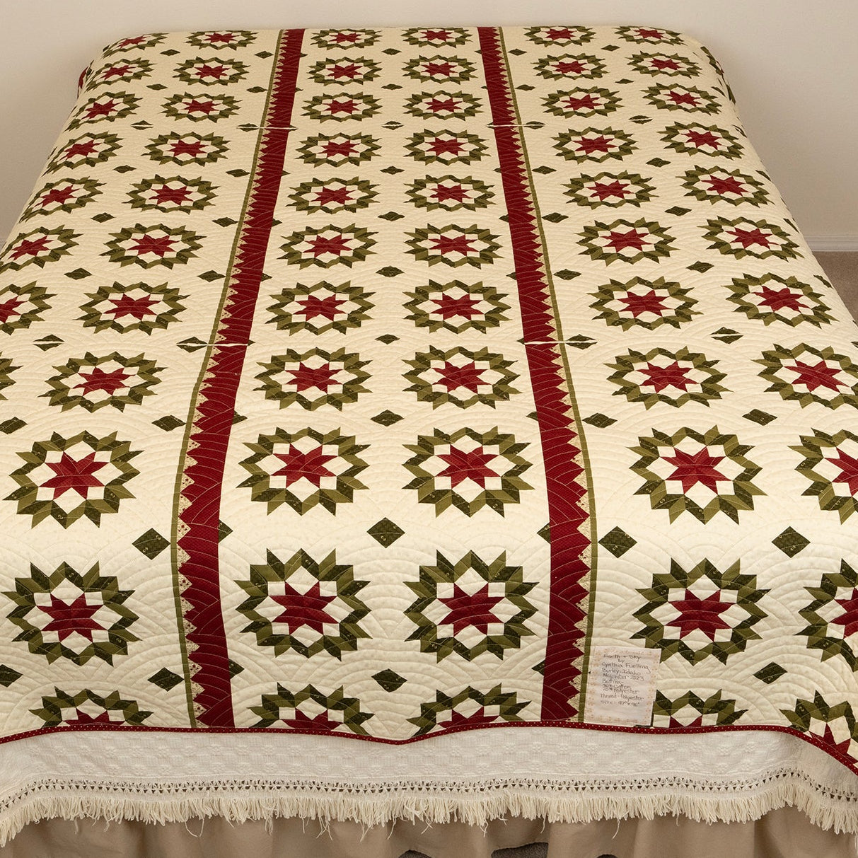 The back side of a quilt with a uniform churn dash pattern in red and green on a neutral base