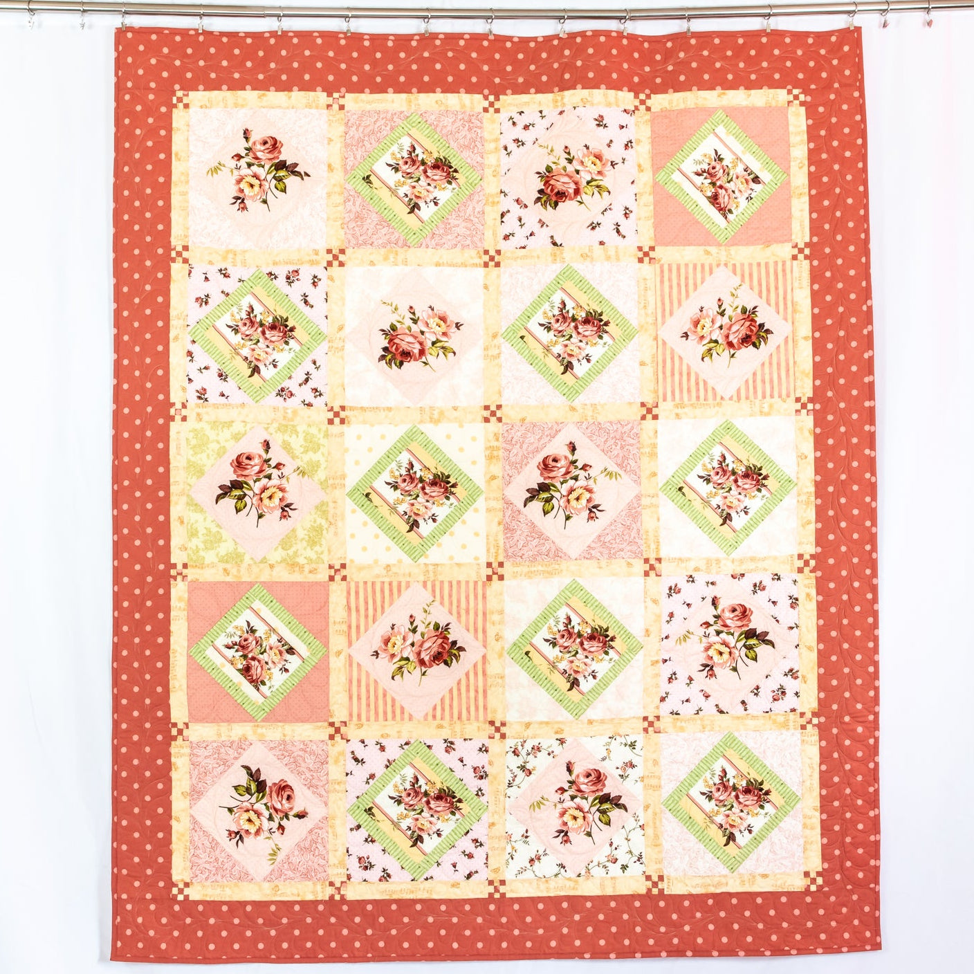 Diamond chequered quilt with polkadot border hanging on a rail. 