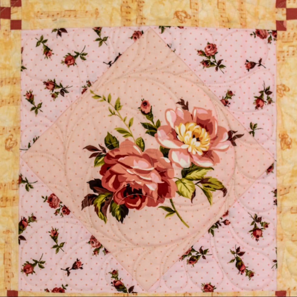 Quilt block made up of a large floral print with music note print border.