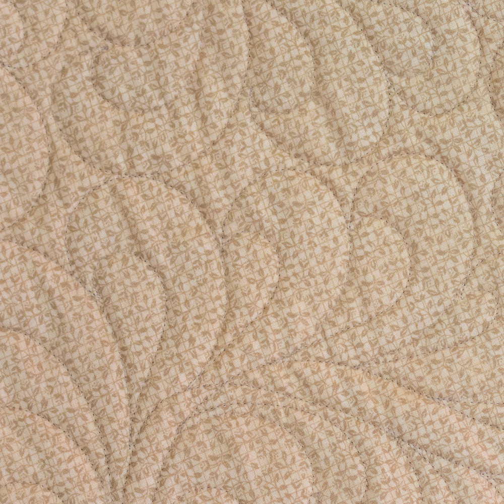 Close up of quilt stitching in a neutral leaf print. 