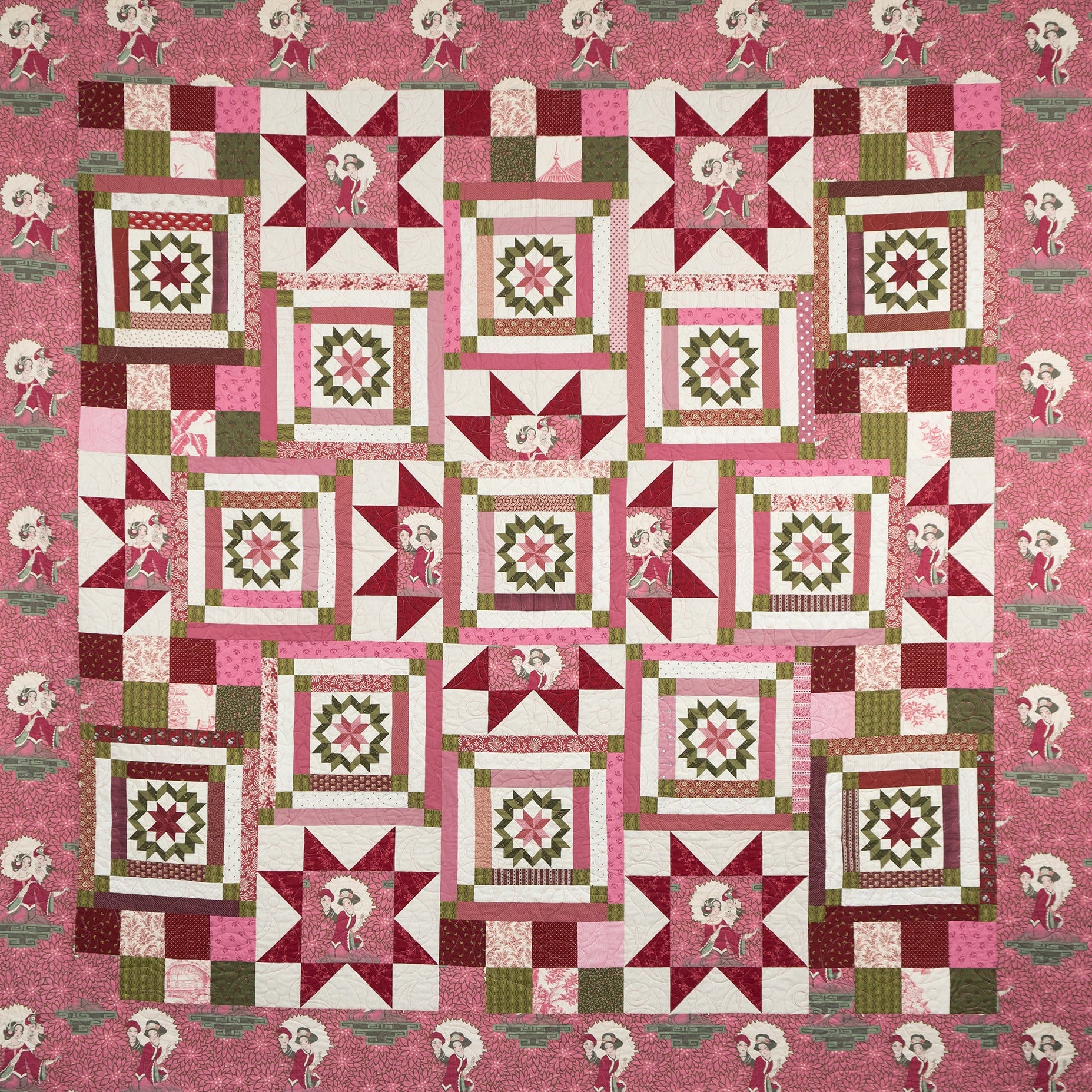 Pink geometric and star printed quilt laid out with empress figures around the border