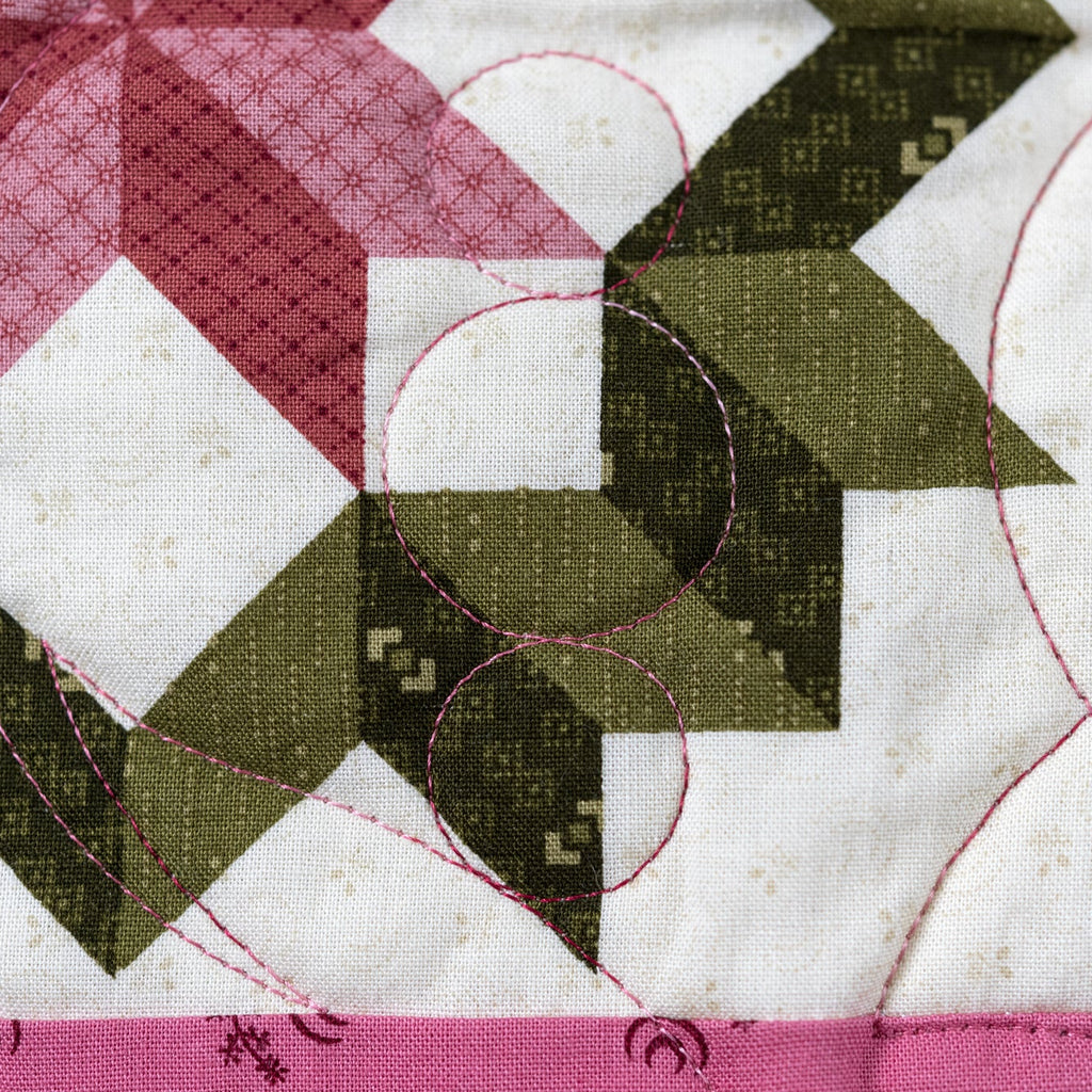 Pink stitching detail on a quilt block in with a green and pink background pattern