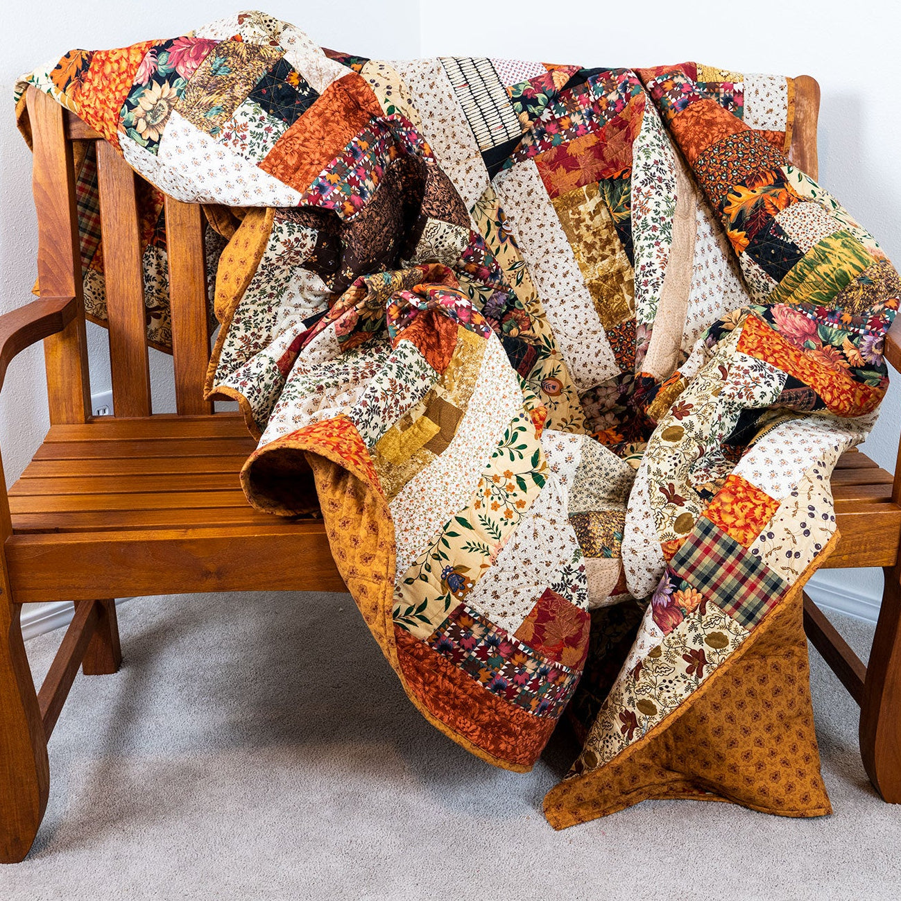 Colorful patchwork quilt draped over a wooden chair against a white wall.