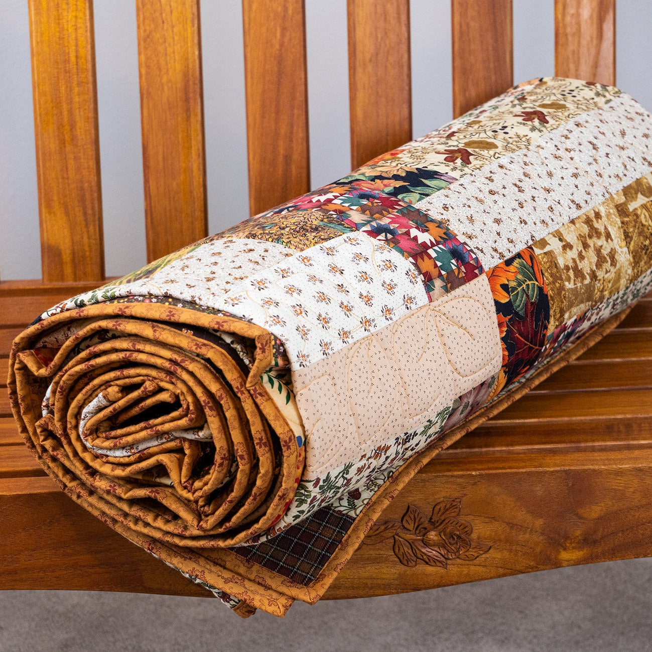 Rolled-up patchwork quilt on a wooden bench