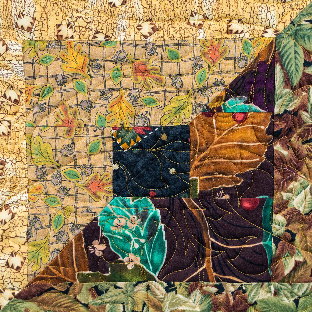 Quilt block with various leaf prints in neutral and purple colours, with intricate leaf stitching. 