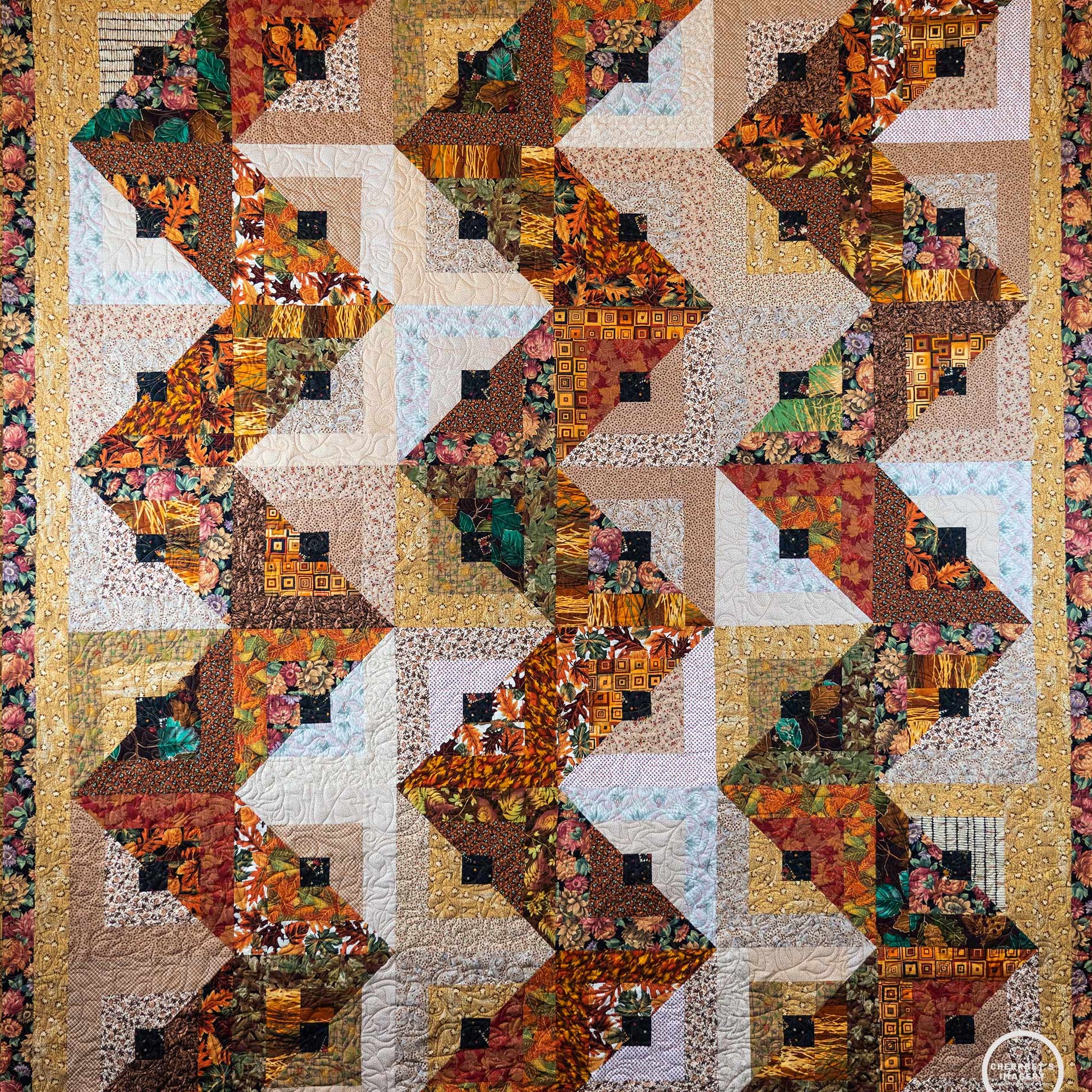 Quilt with a streak of lightening print made up of brown and orange leaf prints with a floral border.