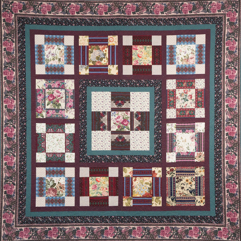 Quilt with floral patterns and a colorful border on a white background