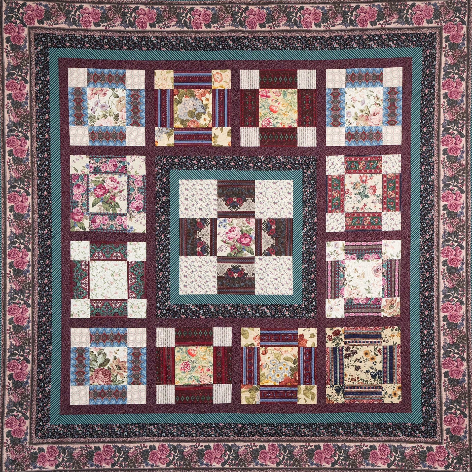 Quilt with floral patterns and a colorful border on a white background