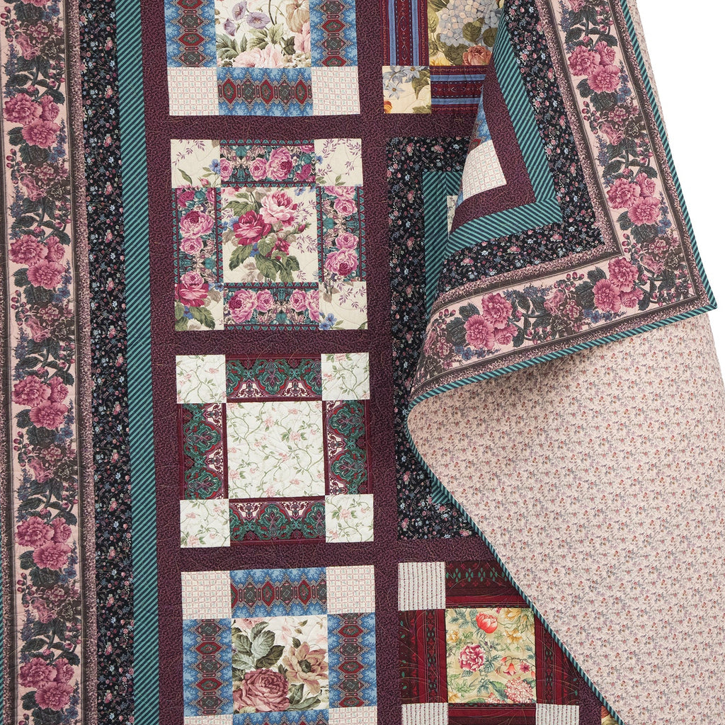 Quilt with floral patterns and a colorful border on a white background