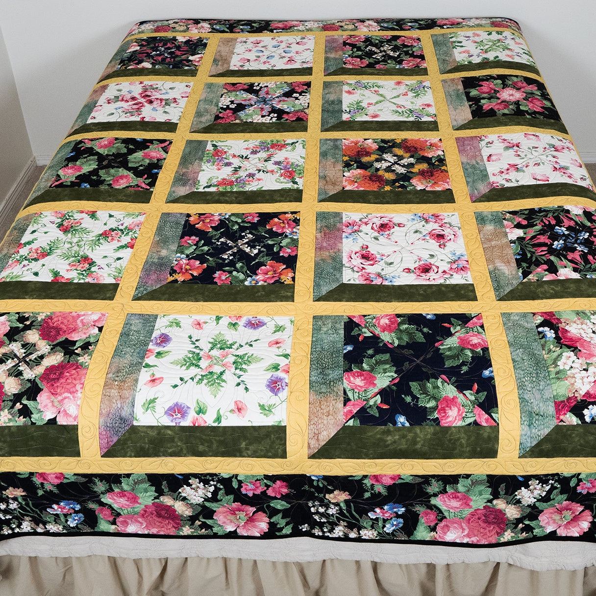 Floral patchwork quilt on a bed with a beige bed skirt.