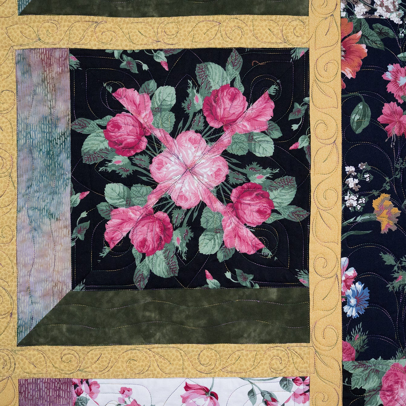 Floral quilt with pink roses and green leaves on a black background, surrounded by other floral patterns.