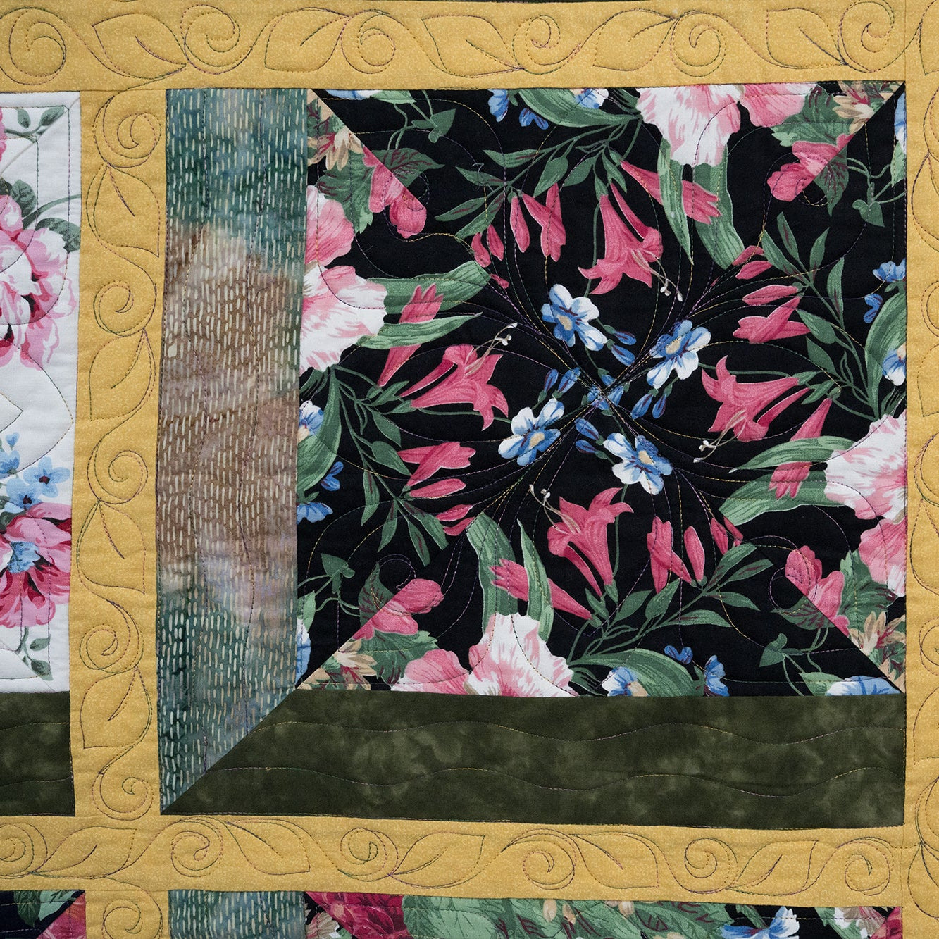 Floral quilt with pink and green flowers on a black background, framed with gold border.