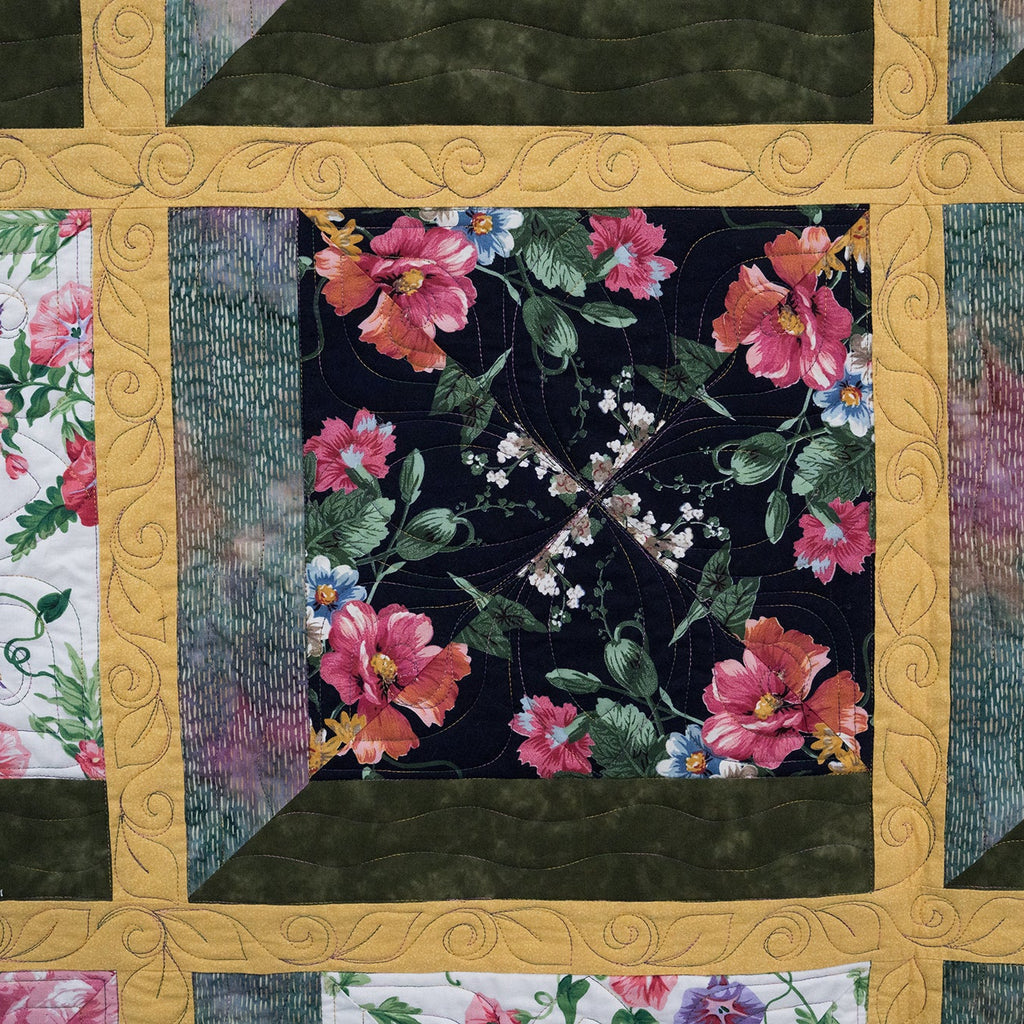 Floral quilt with a gold border featuring various floral patterns.