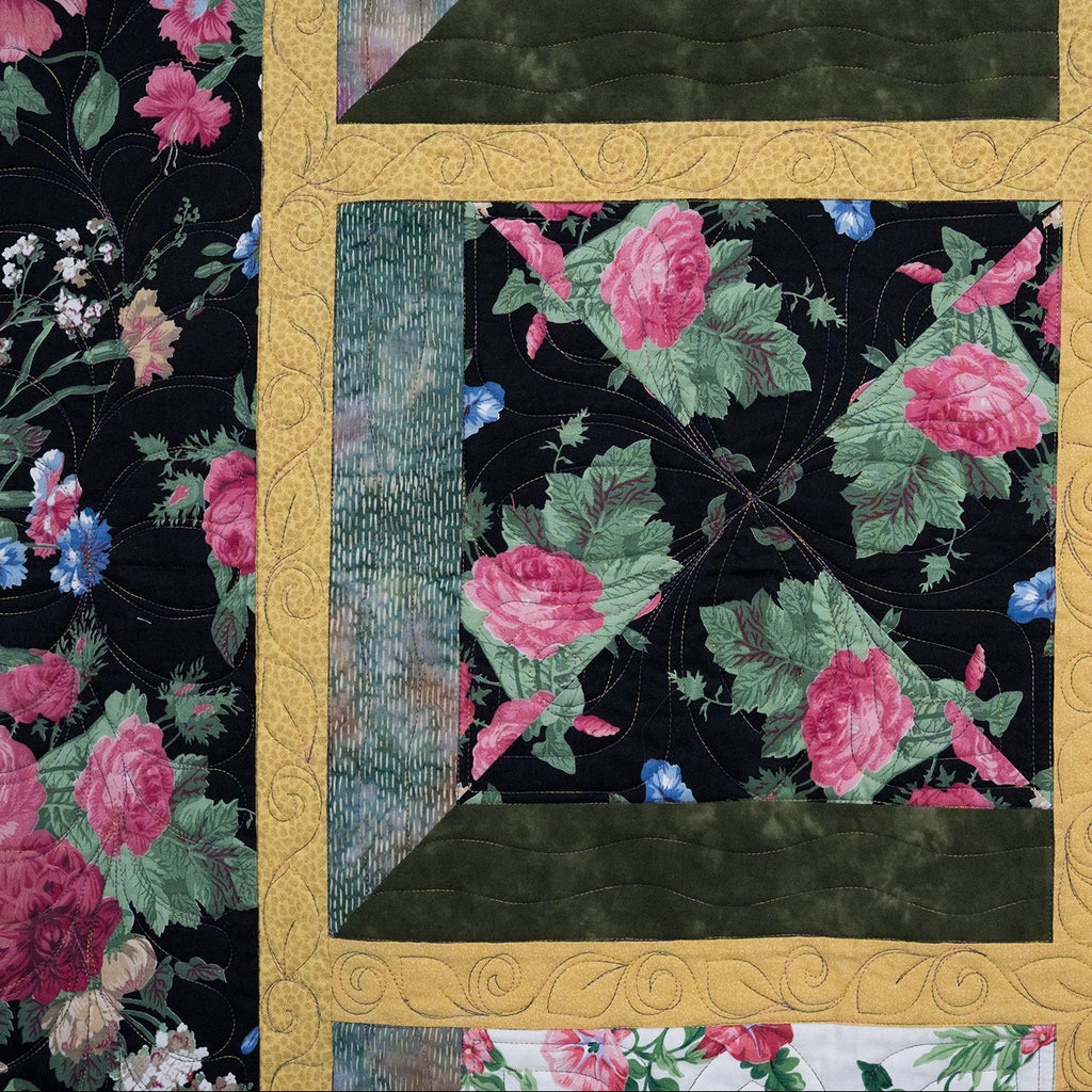 Floral quilt with a gold border featuring pink and green flowers on a black background.