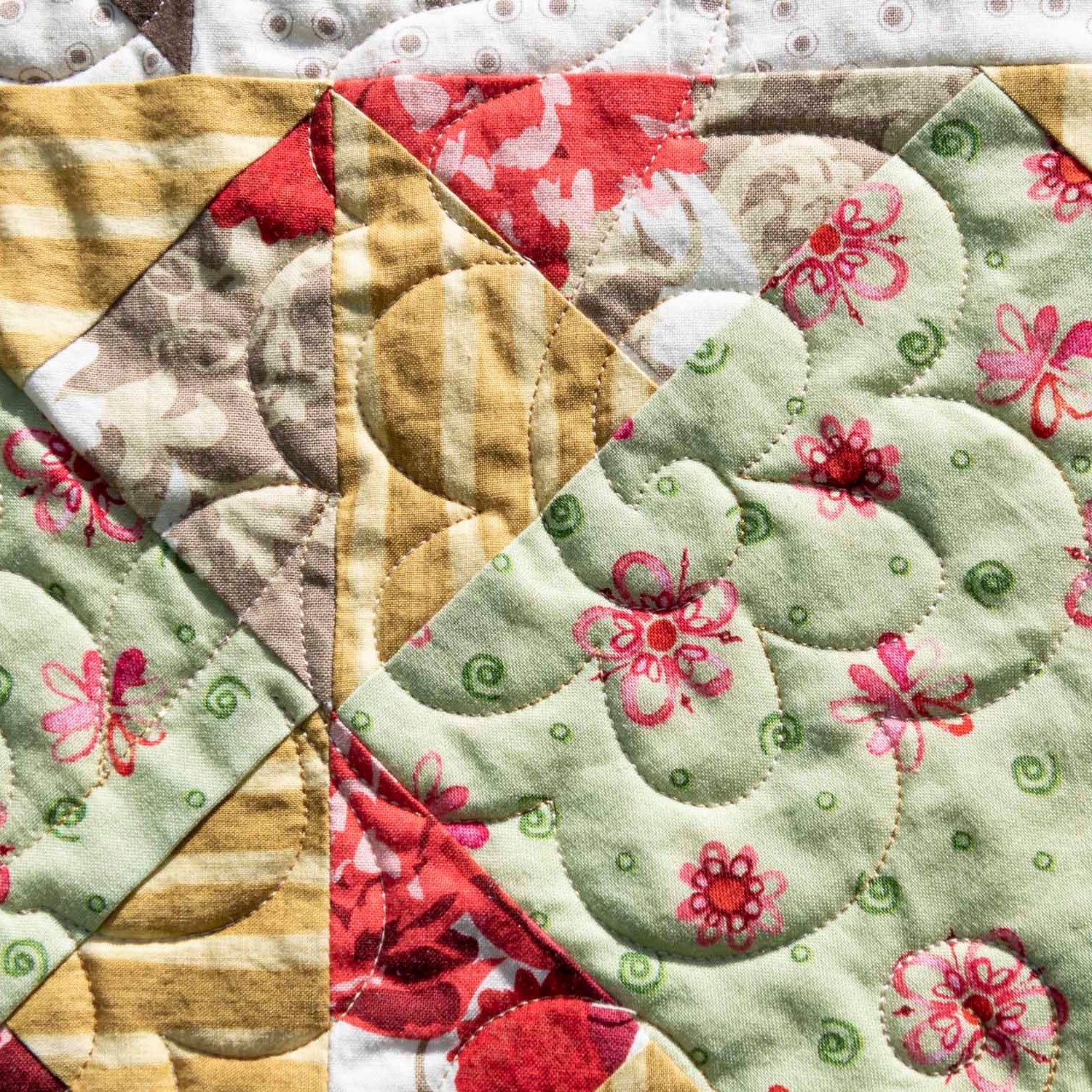 Quilt block with floral patterns in green, red, and beige.